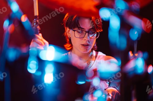 Preview: Young Adult Playing Drums Under Vibrant Stage Lights