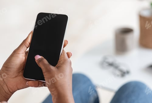 Preview: Unrecognizable Black Woman Using Smartphone With Blank Black Screen At Home