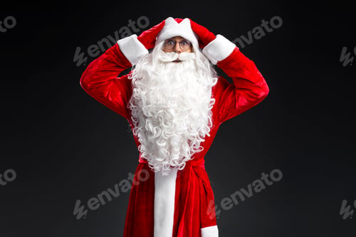 Preview: Funny scared Santa Claus holding head looking at camera isolated on black backgriund