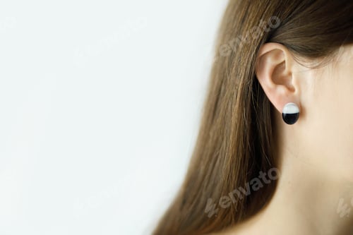 Preview: Beautiful sensual woman with modern geometric earring, close up view. Space for text. Beauty care