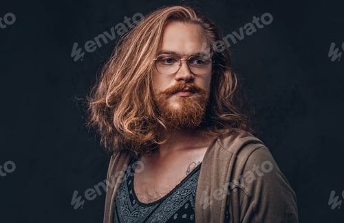 Preview: Portrait of a redhead hipster male in a studio. Isolated on the dark background.