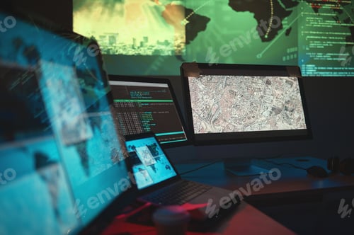 Preview: Computers Displaying Code and Maps in a Dark Room