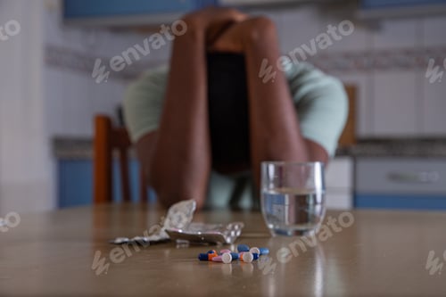 Preview: Desperate man with his head down takes psychiatric drugs to treat depression. Psychiatric pills.