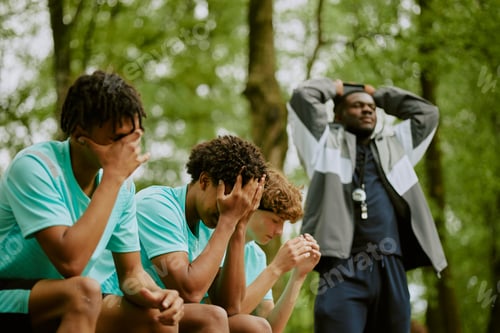 Preview: Multiethnic Teen Boys Sitting on Bench Looking Disappointed after Sports Game