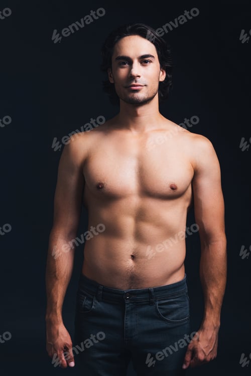 Preview: Charming handsome. Shirtless handsome man looking at camera while standing against black background