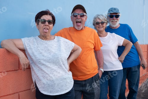Preview: Group of happy senior friends enjoy time together outdoors, sticking their tongues out