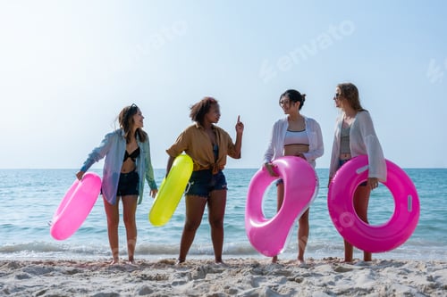 Preview: Group of diverse young women smiling on a sunny beach. Youth Friends Enjoying Sea Splash Together.