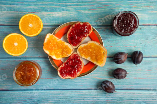 Preview: Orange and plum confiture in a glass jar and on the toast breads in a plate