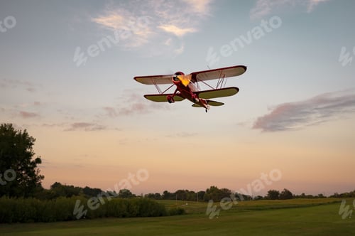 Preview: Low angle shot of a plane flying under a sunset sky
