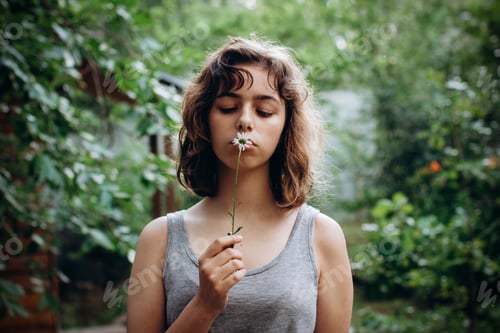 Preview: Teenager Girl sniffing chamomile flower in the forest. Natural beauty. Candid moments
