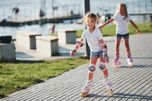 Preview: Two cute kids riding by roller skates in the park at daytime