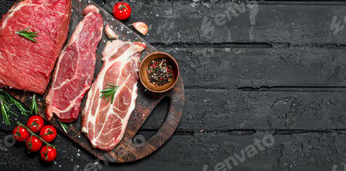 Preview: Raw meat. Beef and pork steaks with spices on the cutting Board.