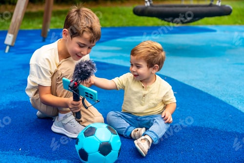 Preview: Children playing videoblogger with phone and microphone at playground