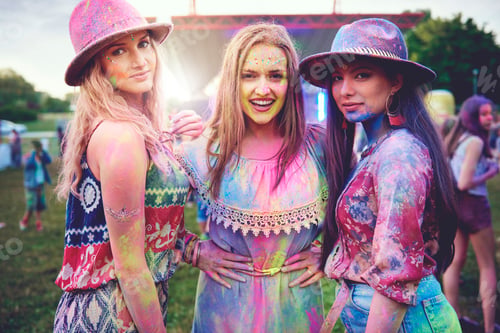 Preview: Portrait of three young boho women covered in coloured chalk powder at festival