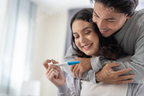 Preview: Asian young couple feeling happy after look at positive pregnancy test.