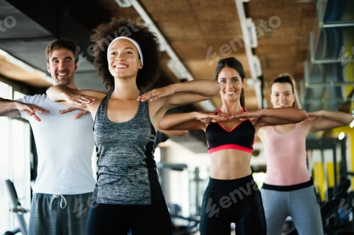 Preview: Group of happy multiracial friends exercising together in gym