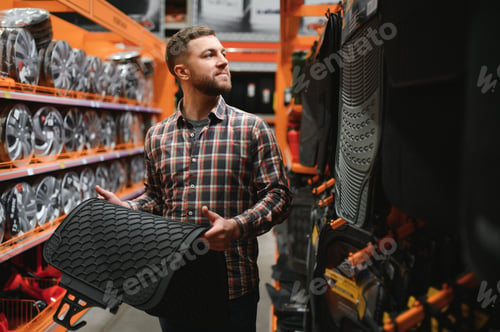 Preview: A man at the car shop or garage choosing floor carpets for his car from given examples