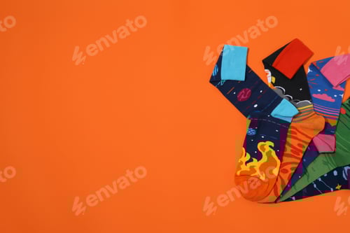 Preview: Bright socks with a print, in a pile on an orange background.