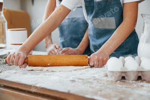 Preview: Close up view of two little girls in blue chef uniform that preparing food on the kitchen