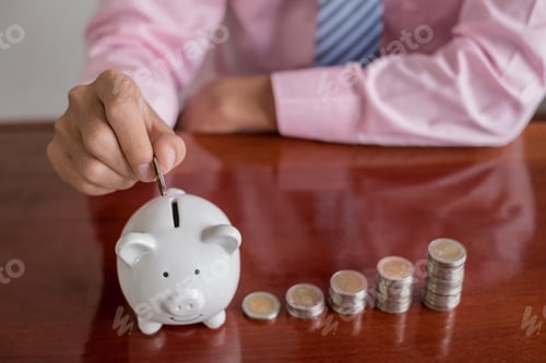 Preview: The hand of a businessman puts coins in a piggy bank, saves money with coins, steps into