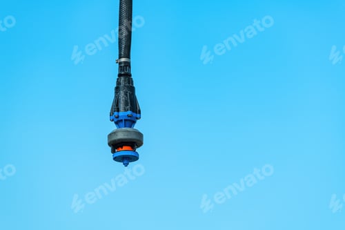 Preview: Agricultural irrigation water sprinkler outdoors against blue sky