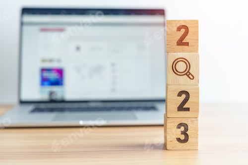 Preview: 2023 block with magnifying glass icon against laptop background.