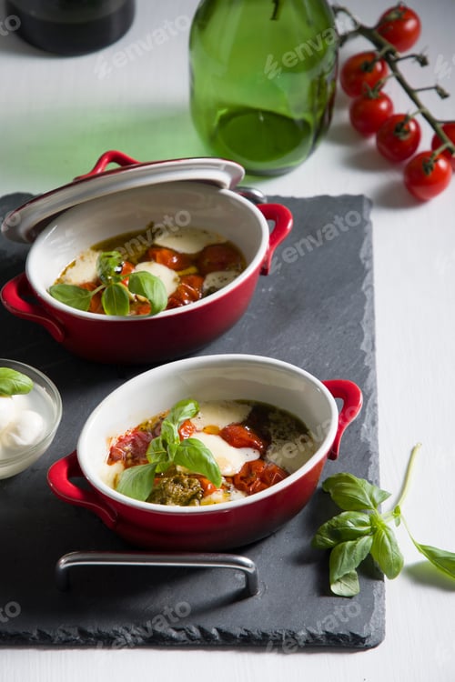 Preview: Italian caprese salad, baked cherry tomatoes, mozzarella and basil on a white table, still life