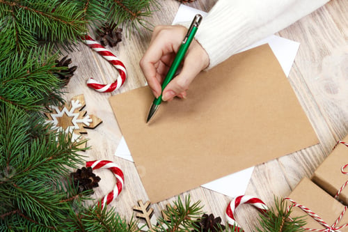 Preview: Female hands writing a letter to Santa Claus. Christmas gifts on a wooden background