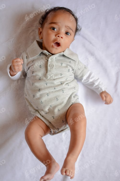 Preview: High angle view of cute baby laying on bed
