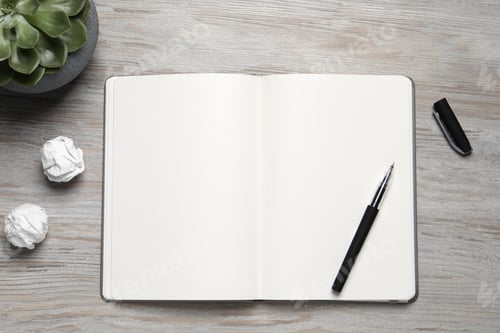 Preview: Open blank notebook, plant, stationery and crumpled paper balls on light wooden table, flat lay