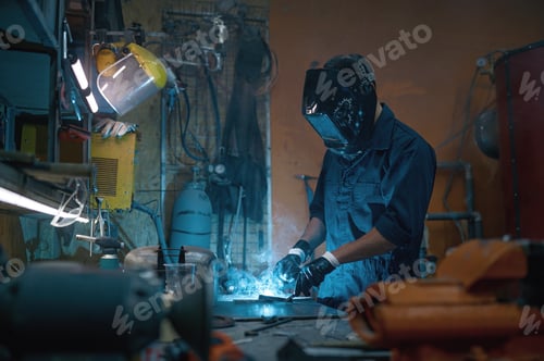 Preview: Repairman wearing protective helmet working with welding at motorcycle workshop