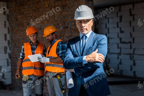 Preview: selective focus of businessman standing with crossed arms near constructors