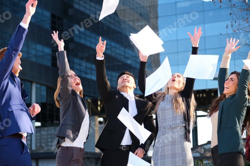 Preview: Cheerful business team throwing papers up in the air celebrating success.
