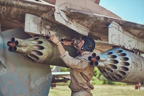 Preview: Mechanic in uniform and flying helmet repair old war fighter-interceptor in an open-air museum.