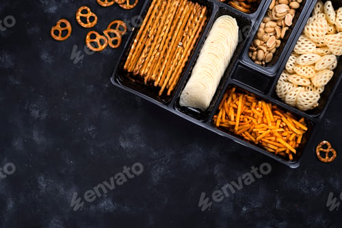 Preview: a variety of snacks on the box for beer on a concrete black table