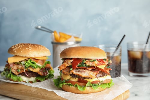 Preview: Tasty burgers with bacon on board against color background