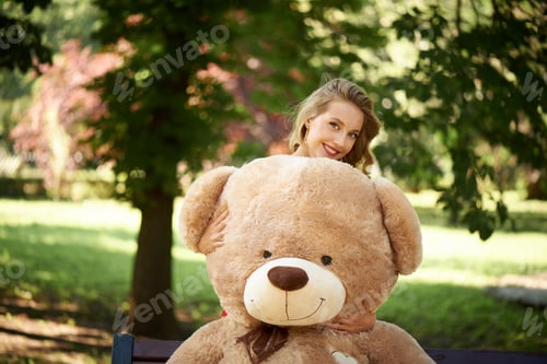 Preview: Young woman with teddy bear in the park.
