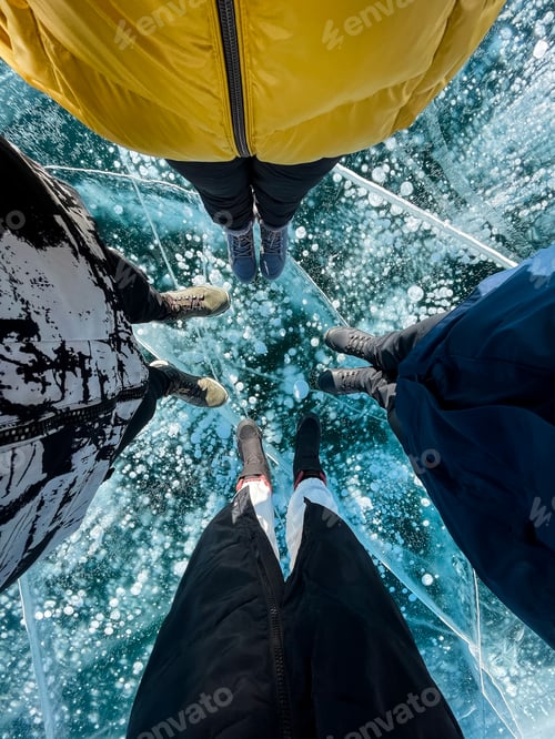 Preview: Fragile thin brittle ice underfoot. Male and female feet on ice.