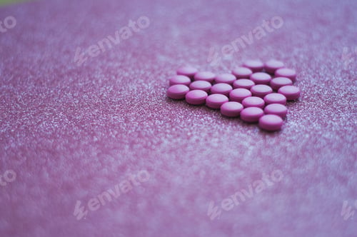 Preview: < NOMINATED > heart-shaped from purple medication tablets on pink glittery background