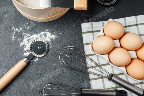 Preview: Baking ingredients and tools arranged on a dark countertop for preparation