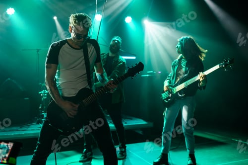 Preview: Rock band performing energetically on stage under green lights