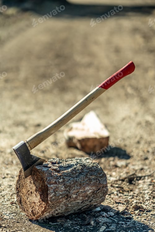 Preview: Vertical shot of an axe on a tree trunk on background of a roadway