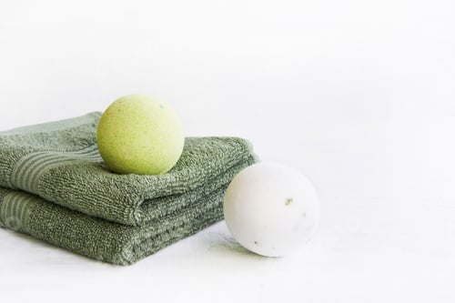 Preview: SPA concept. Bath bombs and green towels on light background. Copy space for text