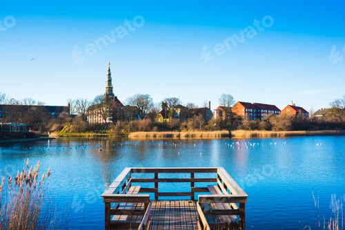 Preview: View of wooden pier on river and distant church spire, Copenhagen, Denmark