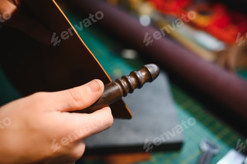 Preview: Production process. Young focused experienced master craftsman makes leather goods at his workplace