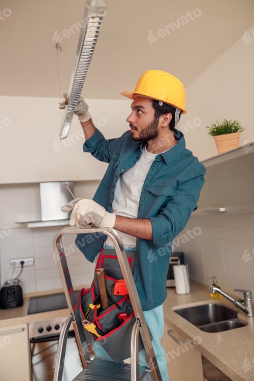 Preview: Professional electrician worker in uniform is installing electric lamps light in kitchen