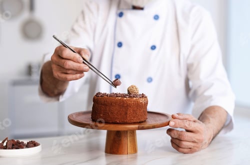 Preview: Elderly pastry chef decorating tasty cake at table in kitchen, closeup