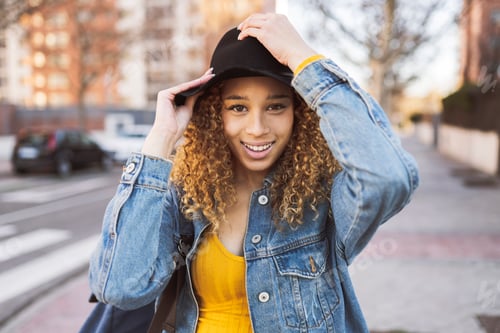 Preview: pretty curly haired hispanic woman backpacker traveler wearing hat traveling around the city