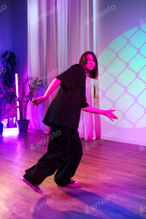 Preview: Dancer showcasing contemporary moves in colorful studio setting during evening performance