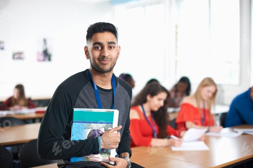 Preview: Portrait of student in classroom holding textbook looking at camera smiling